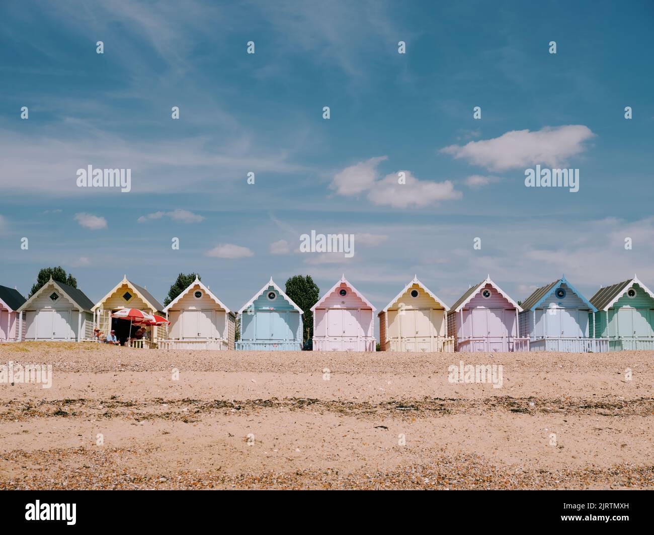 The pastel painted summer beach huts and blue sky on the beach in West Mersea, Mersea Island, Essex, England UK Stock Photo