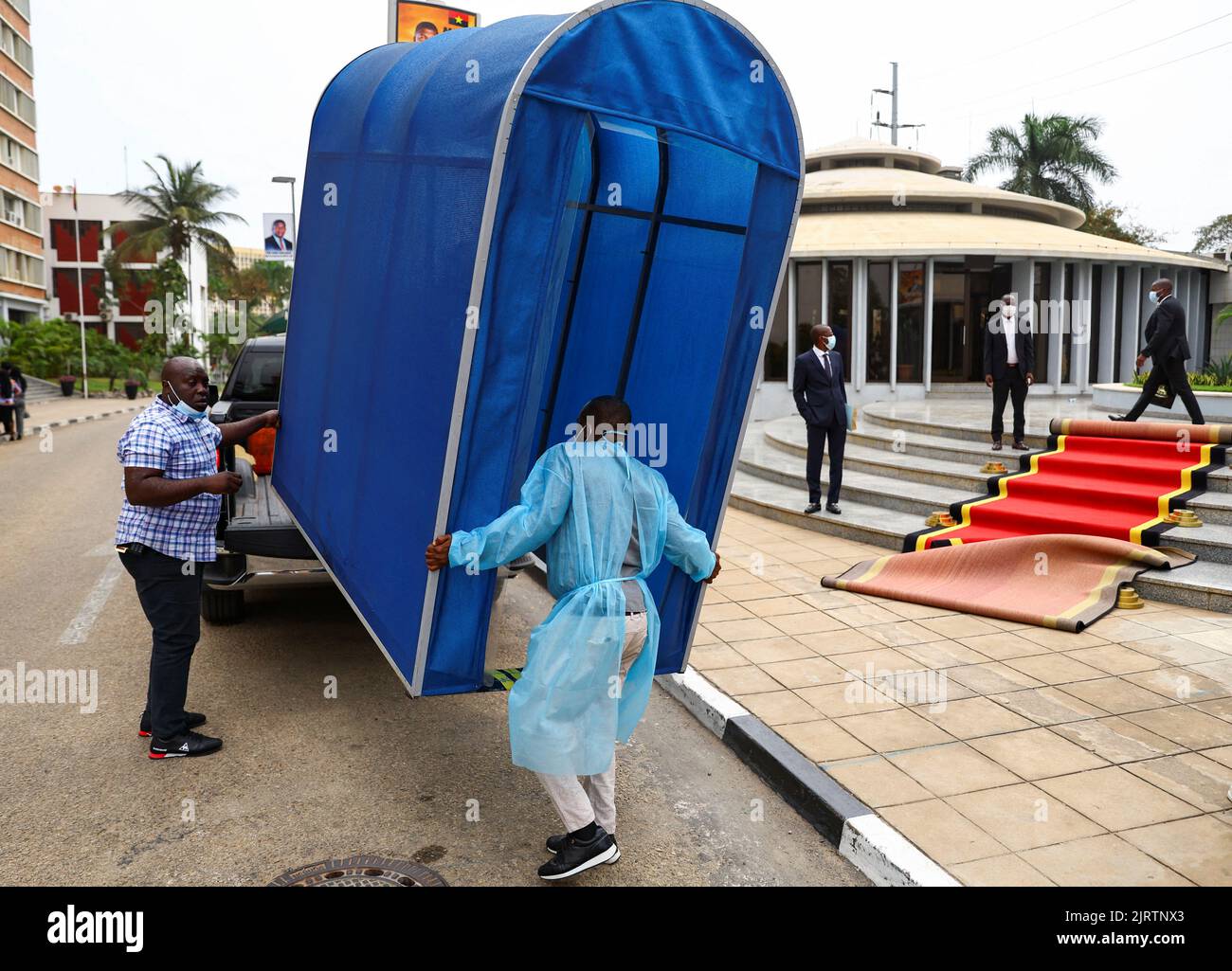 A worker wearing protective clothing loads equipment after Angola's president and leader of the ruling MPLA Joao Lourenco left after a meeting at the party's headquarters in the capital Luanda, Angola August 26, 2022. REUTERS/Siphiwe Sibeko Stock Photo