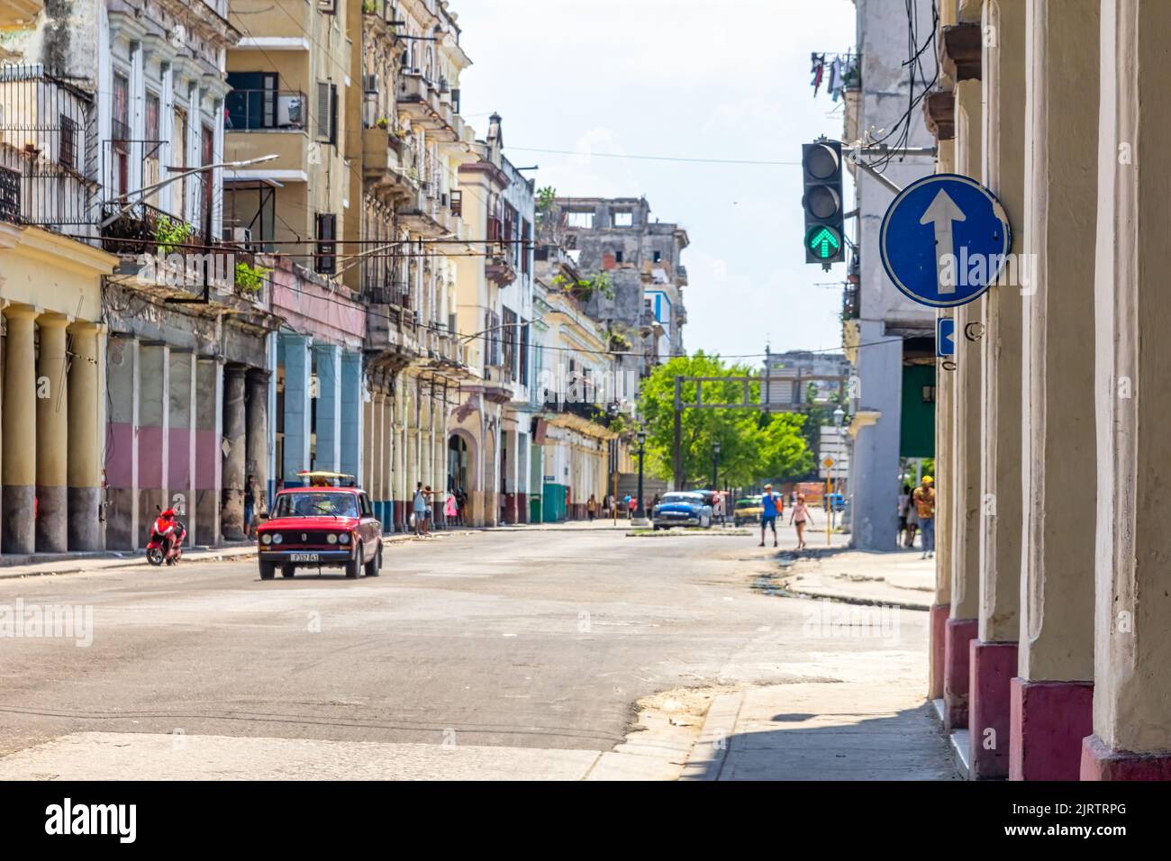 A LADA car drives in a city street where weathered building facades line up Stock Photo