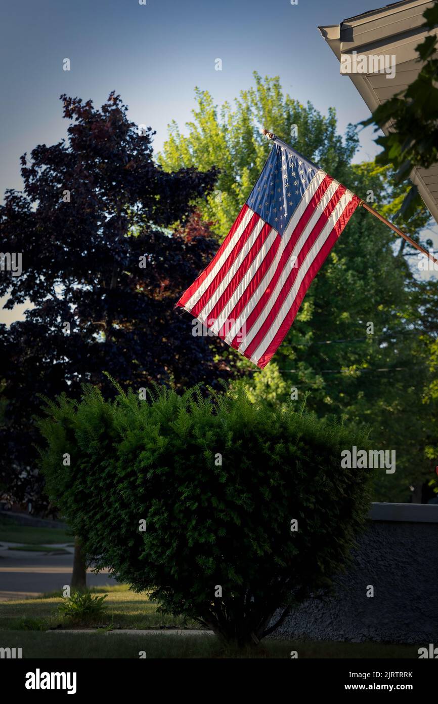 The morning sun shines through the trees on an American flag at Manitowoc, Wisconsin. Stock Photo