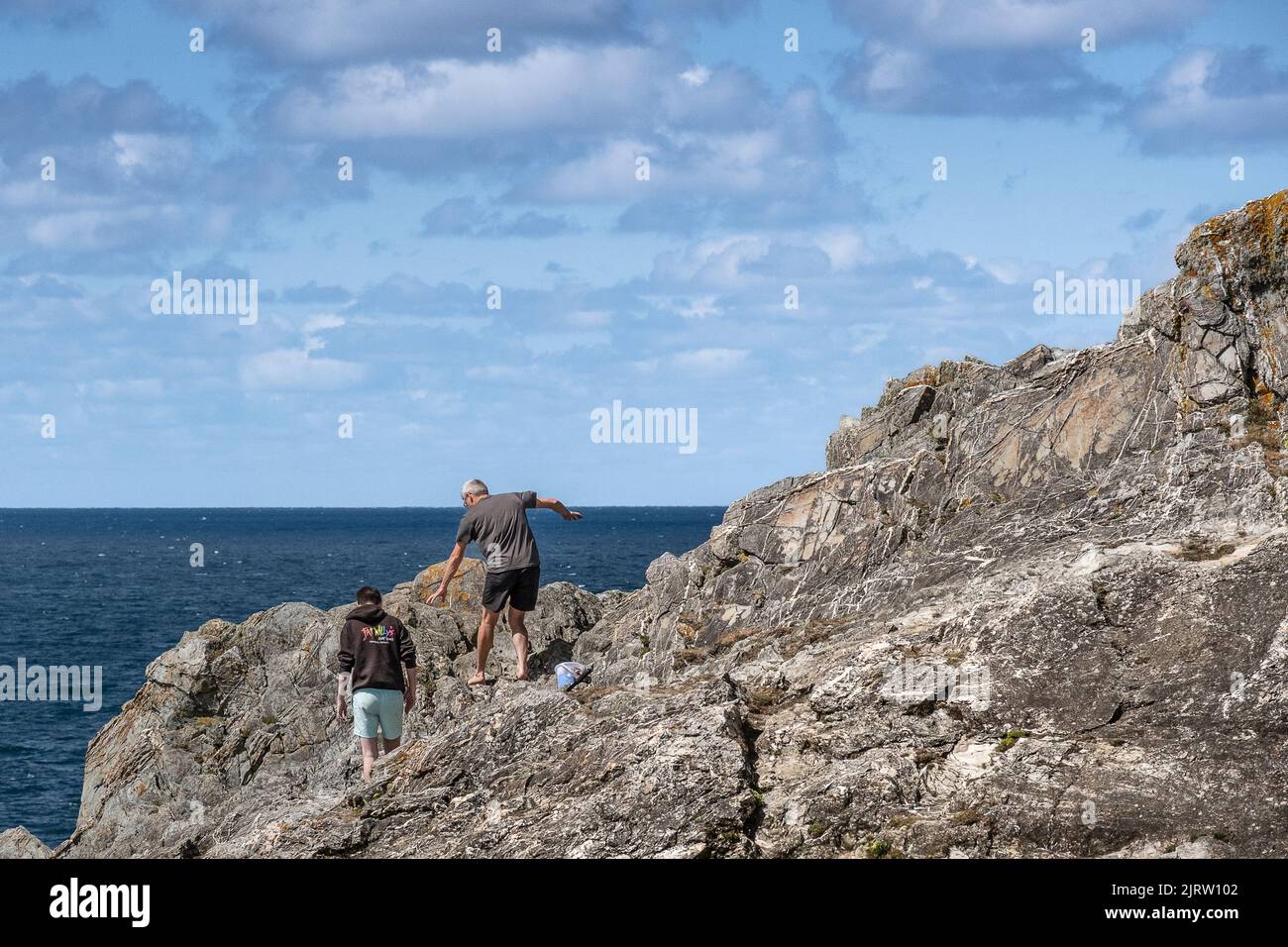 Holidaymakers walking carefully on rocks on the coast of Pentire Point East in Newquay in Cornwall. Stock Photo