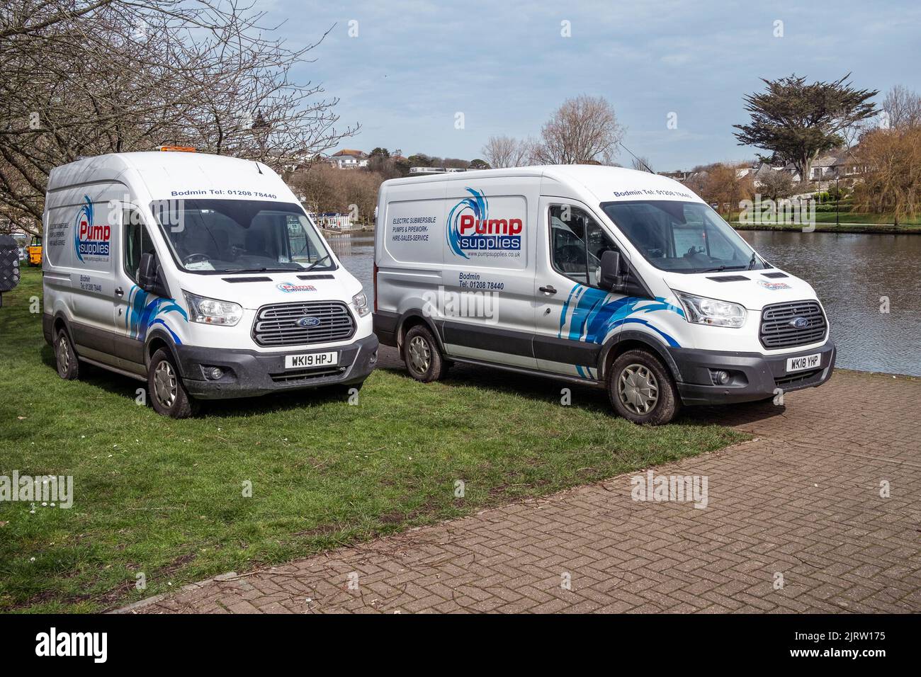 Two vehicles from a local Cornish company called Pump Supplies parked at Trenance Boating Lake in Newquay in Cornwall in the UK. Stock Photo
