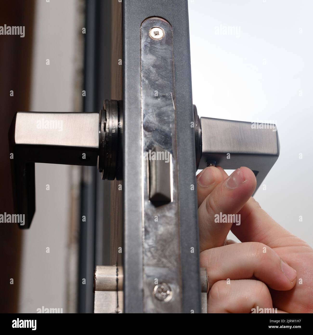 The craftsman installs the door handle with the help of a sprocket key