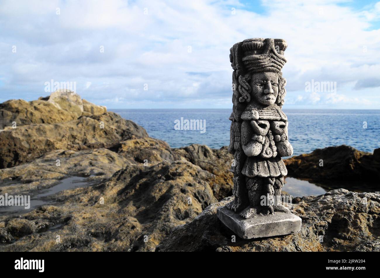 Ancient Maya Statue on the Rocks near Ocean Stock Photo