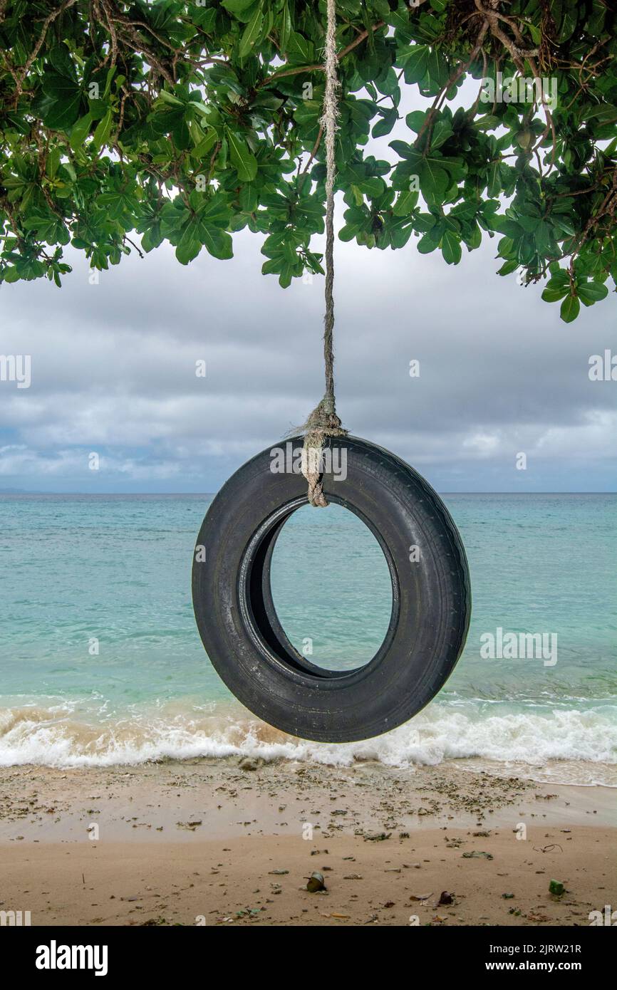 Local Fijian's built a homemade tire swing on a remote beach with a fantastic view. Stock Photo