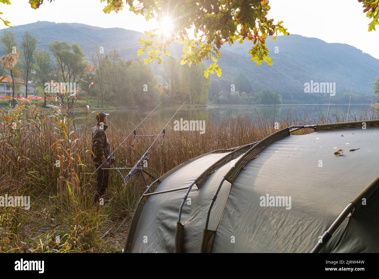 Fishing adventures, carp fishing. Camping on the lake at sunrise. Man at sunrise with tent. Vacation concept Stock Photo