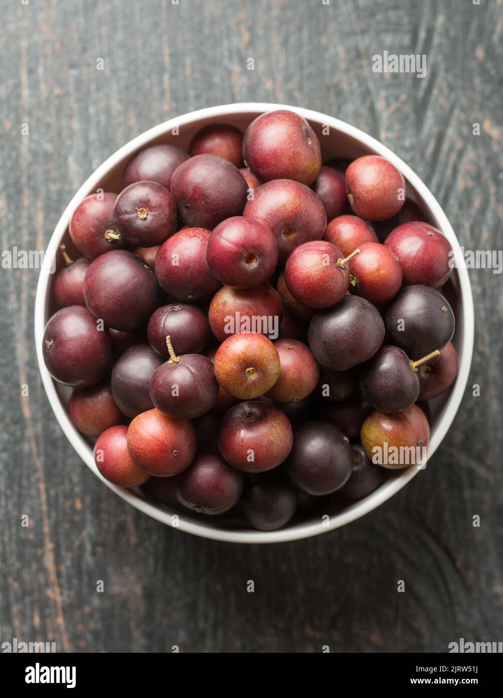bowl full of governor's plum fruits, flacourtia indica, also known as ramontchi, madagascar plum or indian plum,reddish black fleshy fruits Stock Photo