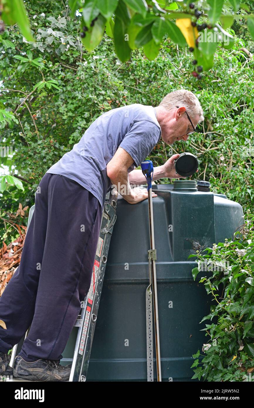 man checking level of domestic fuel oil tank in garden united kingdom Stock Photo