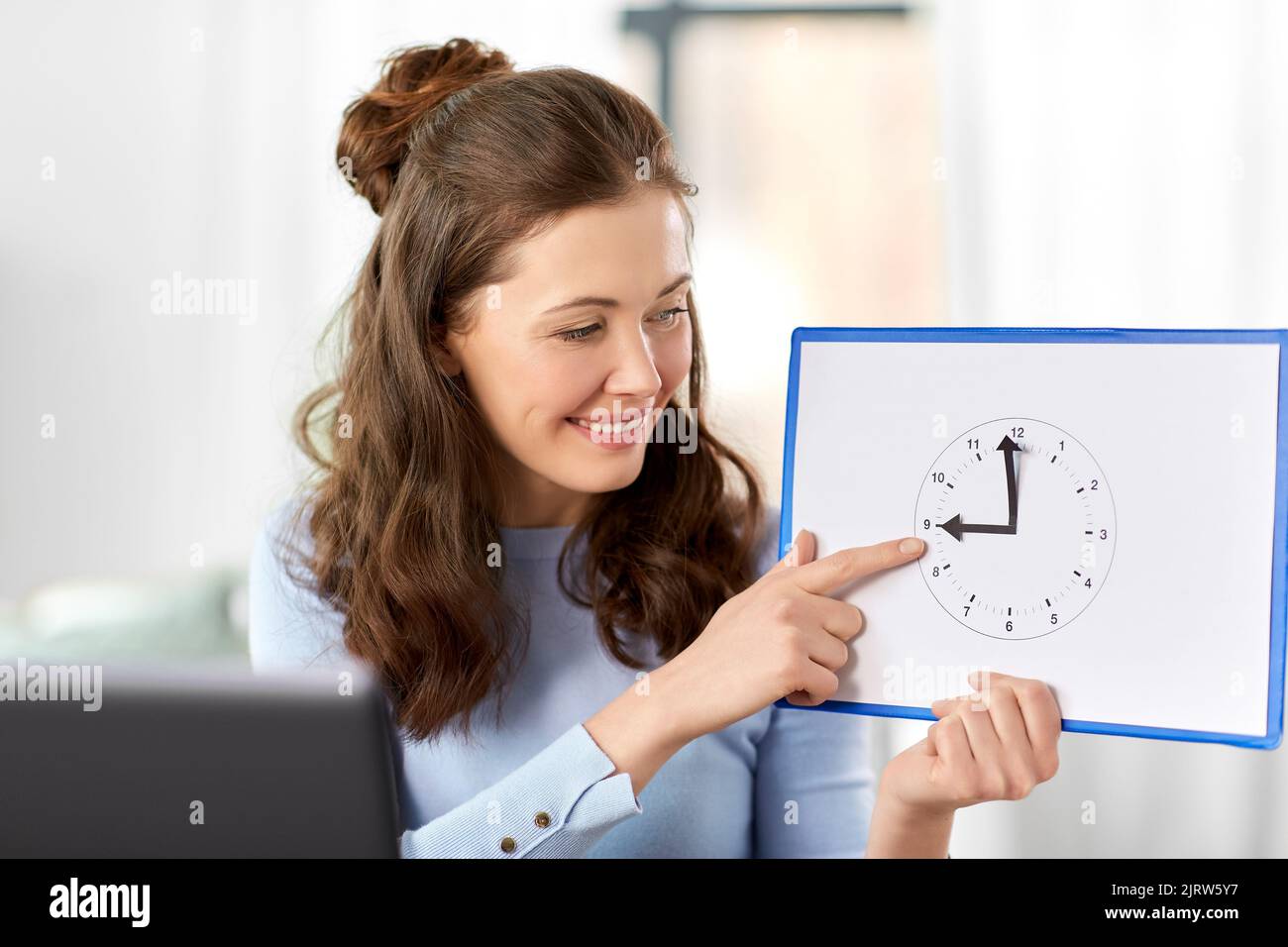 teacher with clock having online class at home Stock Photo