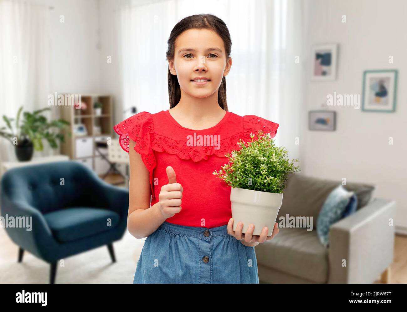 happy girl holding flower in pot showing thumbs up Stock Photo - Alamy