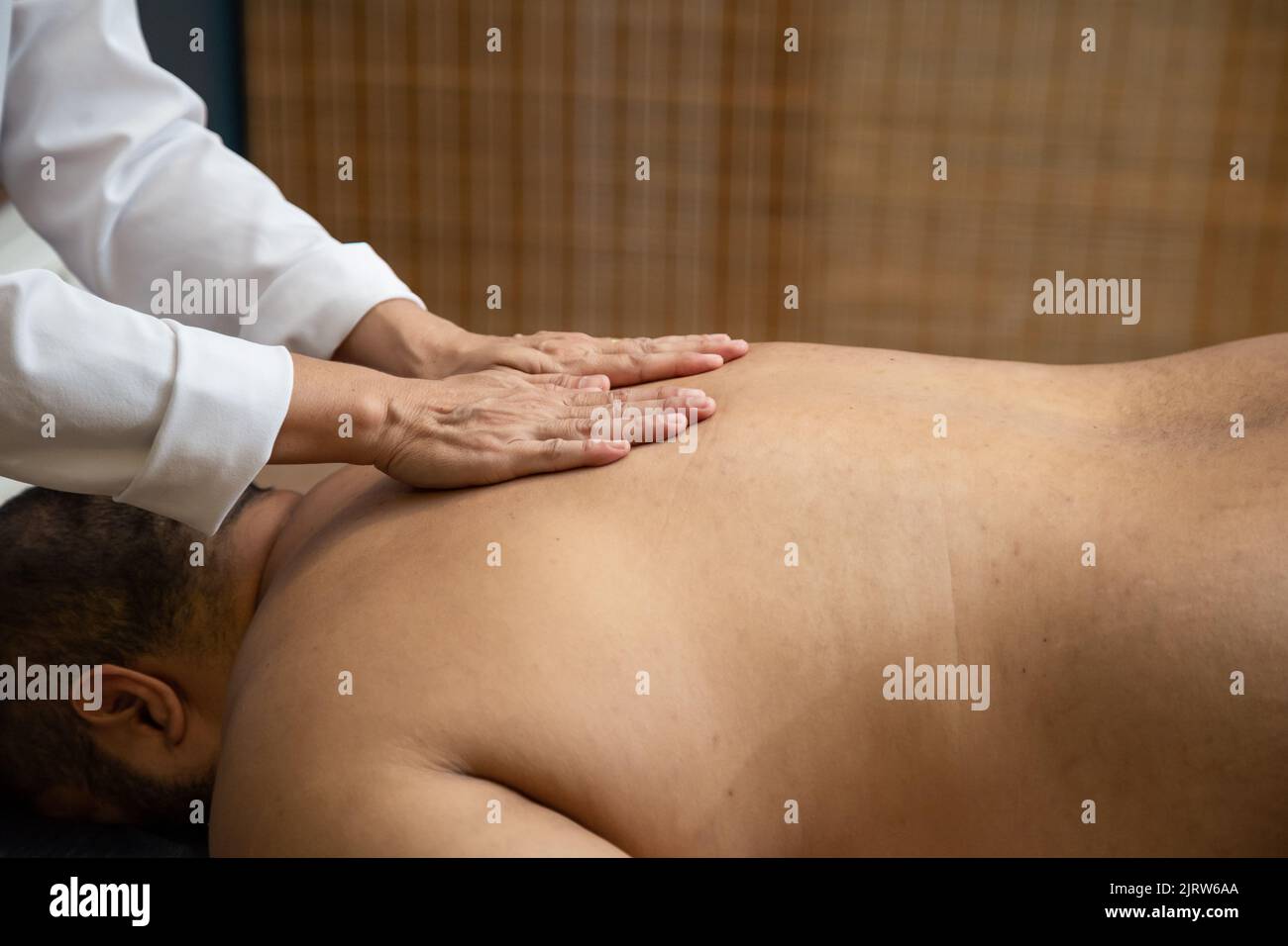 Goiânia, Goias, Brazil – July 18, 2022: A professional doing therapeutic massage on the back of the patient who is lying on the stretcher. Stock Photo