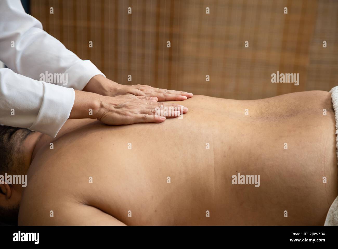 Goiânia, Goias, Brazil – July 18, 2022: A professional doing therapeutic massage on the back of the patient who is lying on the stretcher. Stock Photo