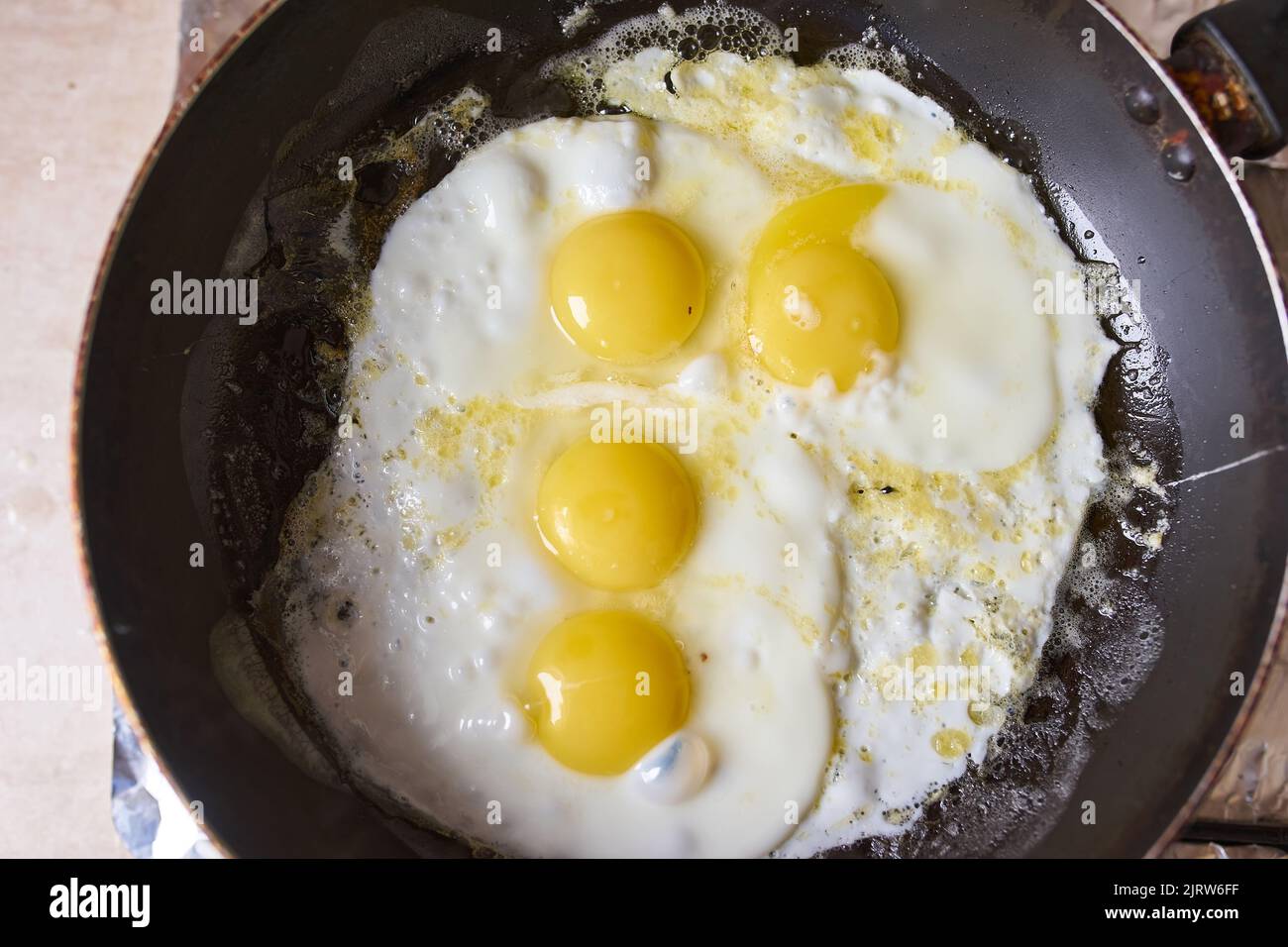 Four eggs are fried in a black pan on the gas stove Stock Photo Alamy