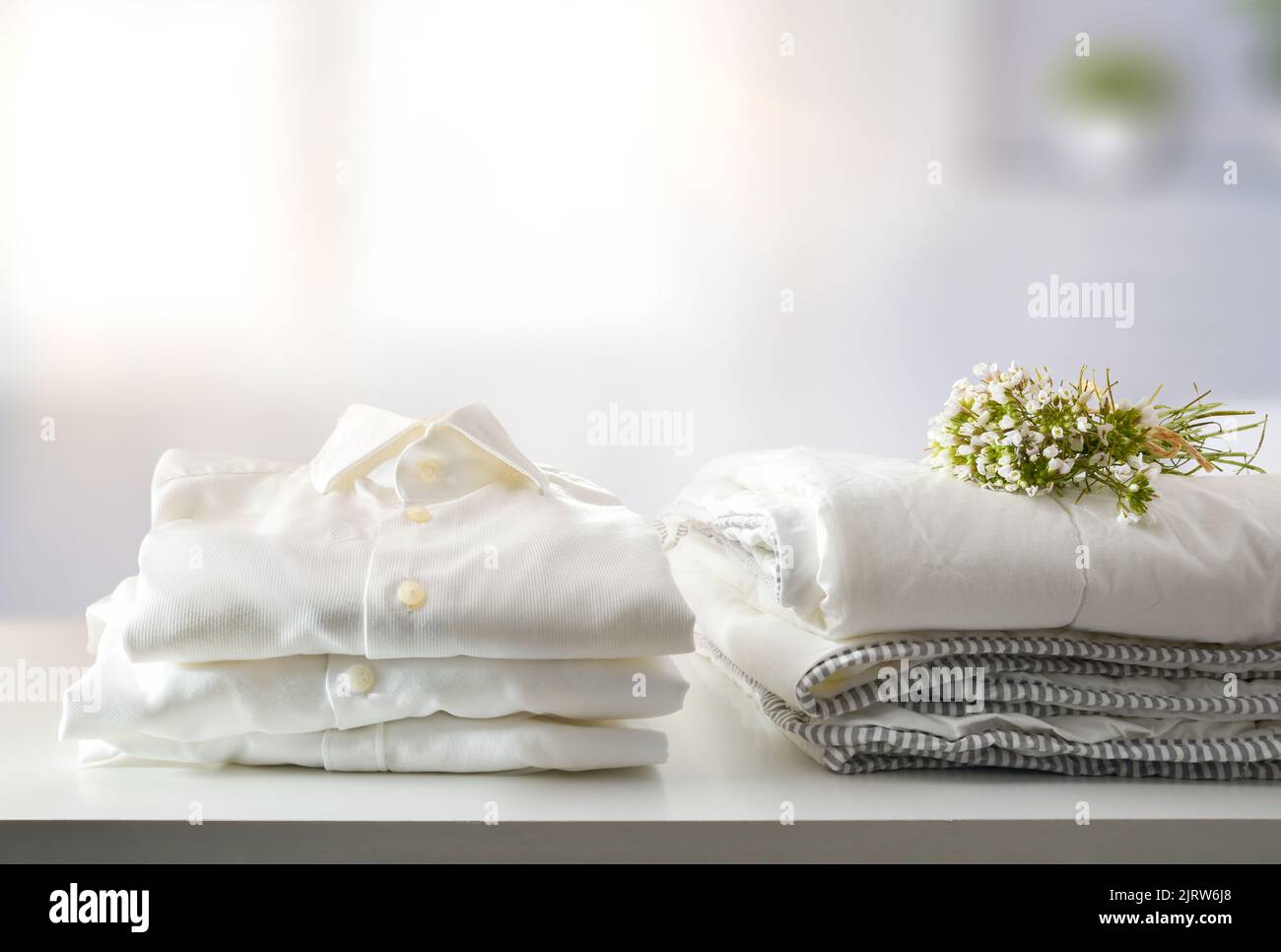 Clean white freshly washed and folded bed and dress clothes on white shelf in bedroom. Front view. Horizontal composition. Stock Photo