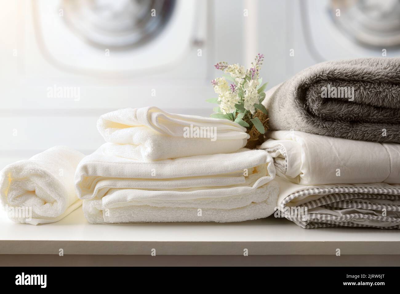 Self-service laundry for the public with bedding and staff on a white bench and professional washing machines in the background. Front view. Horizonta Stock Photo