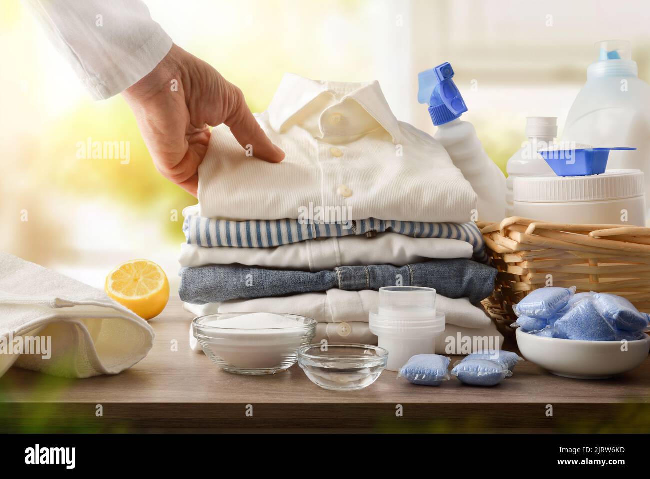 Products and person showing freshly washed clothes in a room with a window in the background. Front view. Horizontal composition. Stock Photo