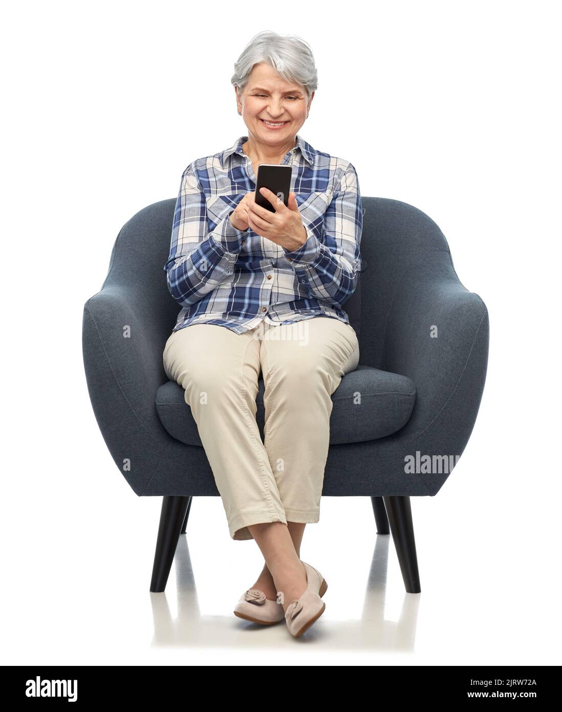 smiling senior woman with smartphone in chair Stock Photo