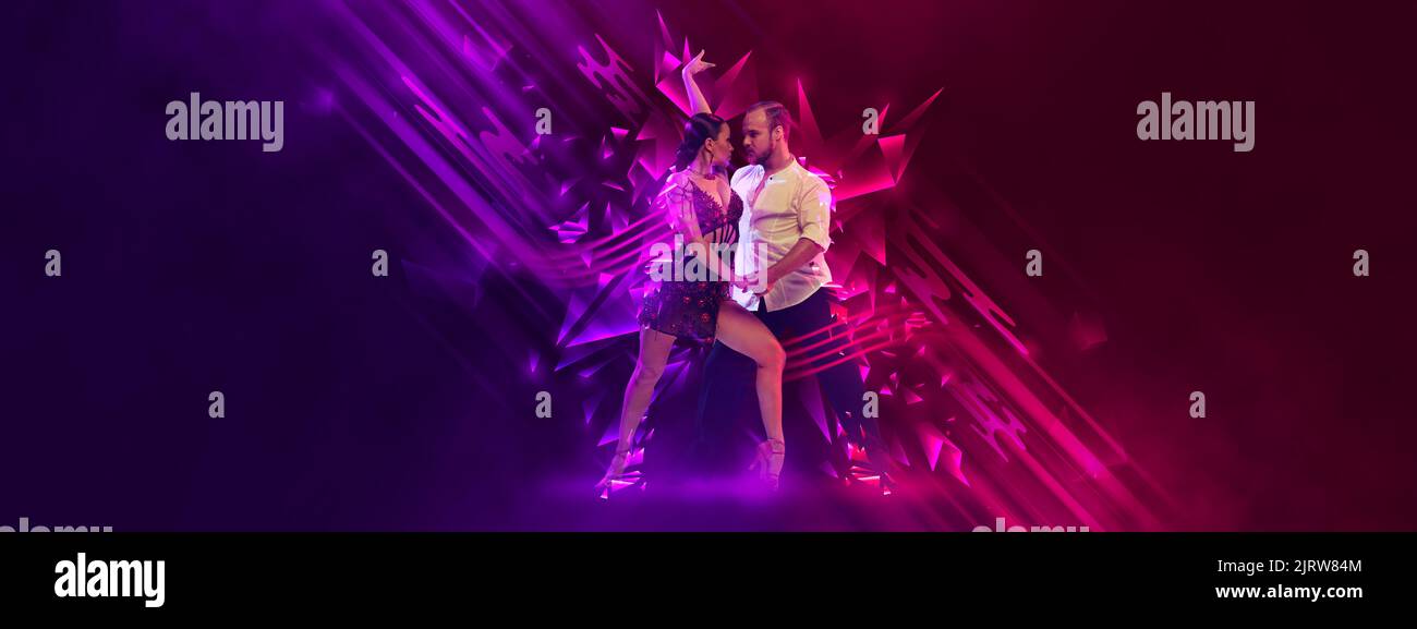 Stylish young couple dancing samba, cha-cha-cha, rumba, paso doble over dark background with neon fluid elements. Art, beauty, dance concept Stock Photo