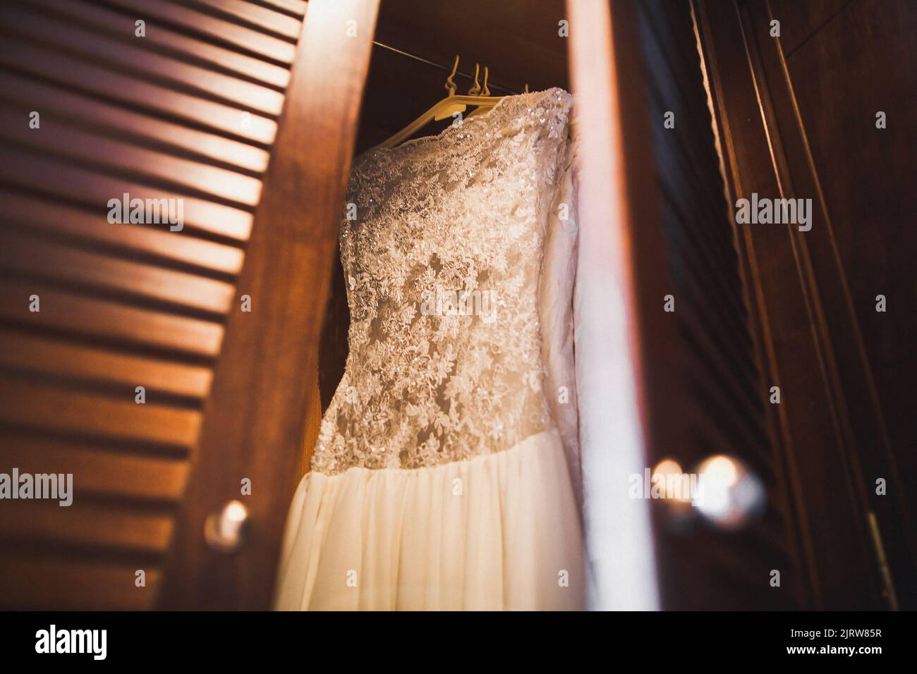 Wedding dress hanging on a wooden wardrobe Stock Photo - Alamy