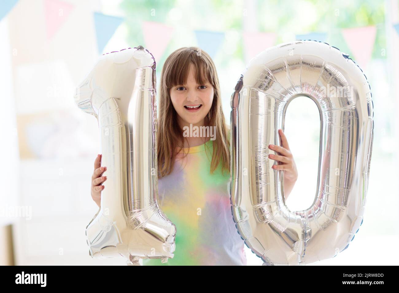 Kids birthday party. Child blowing out candles on colorful cake. Little
