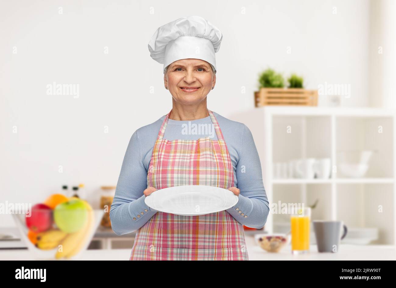 smiling senior woman or chef holding empty plate Stock Photo