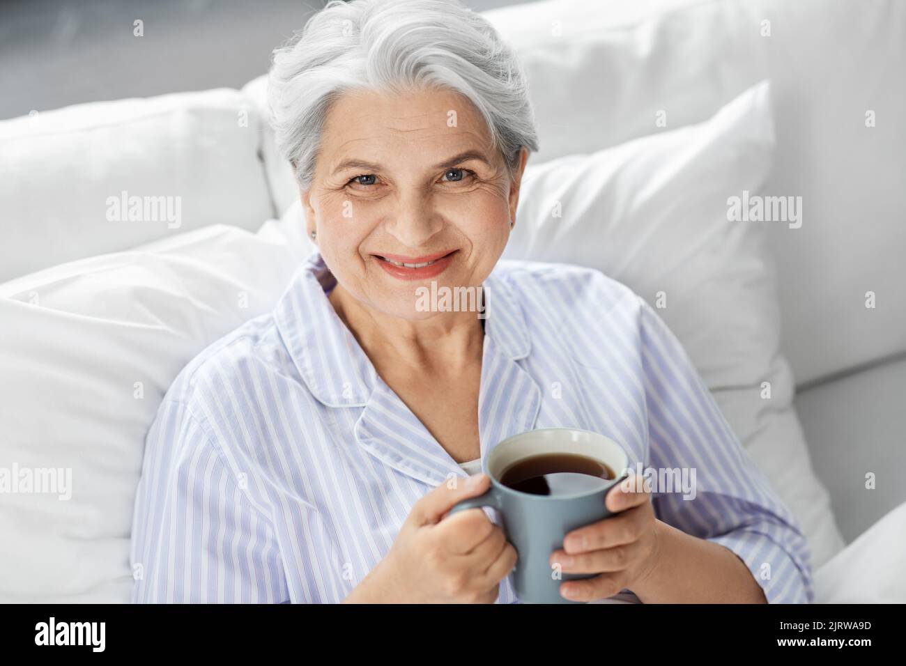 old woman with cup of coffee in bed at home Stock Photo Alamy