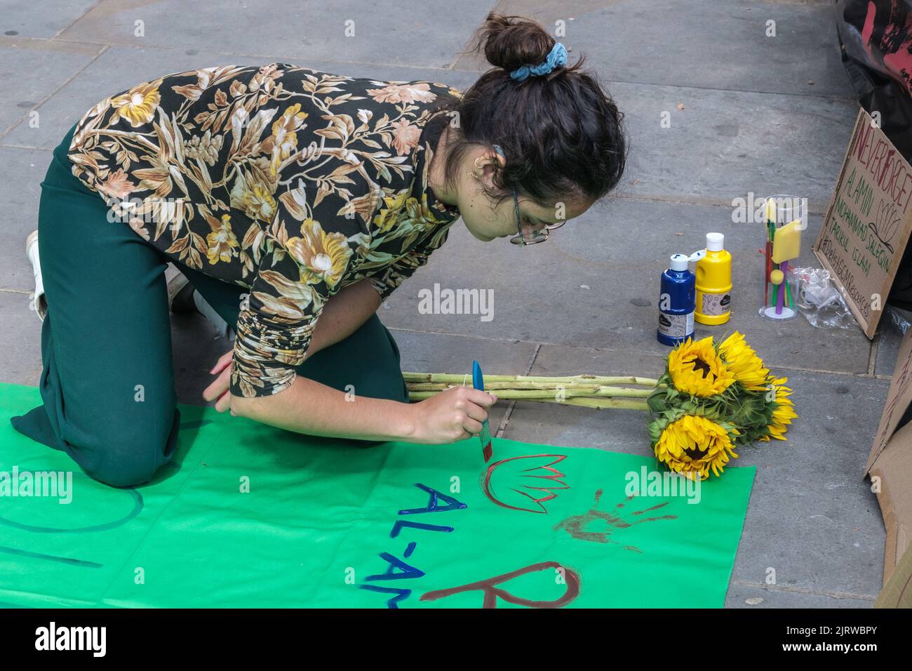 London, UK. 26th Aug, 2022. A woman paints a tribute at Phulbari Solidarity Group vigil at the Bangladesh High Commission on the 16th anniversary of the Phulbari Massacre. 3 people were shot dead at a huge non-violent protest against London mining company GCM's plans to forcibly displace 130,000 people and open cast mine 572 million tons of coal over 30 years. GCM still sells shares on the London Stock Exchange despite having no contract to mine. Credit: Peter Marshall/Alamy Live News Stock Photo