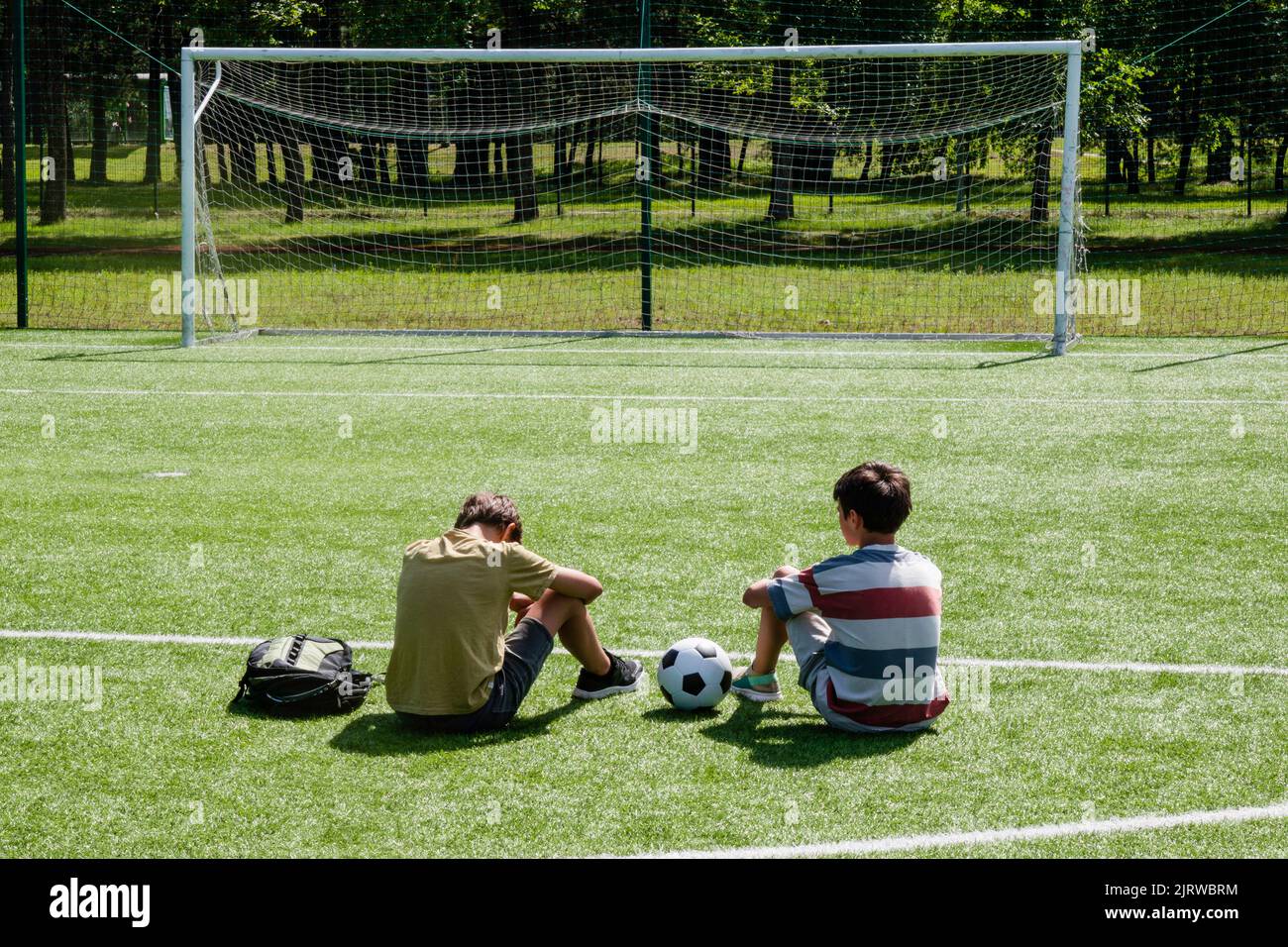 Teenagers talking in school stadium outdoors. Teenage boy comforting consoling upset sad friend. Education, bullying, conflict, problems at school Stock Photo