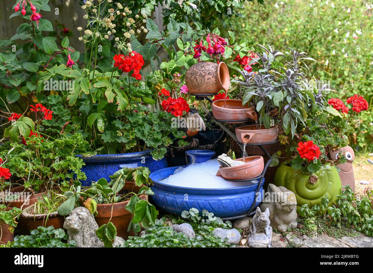 Garden water feature powered by a solar panel being cleaned out using detergent making bubbles in the water Stock Photo