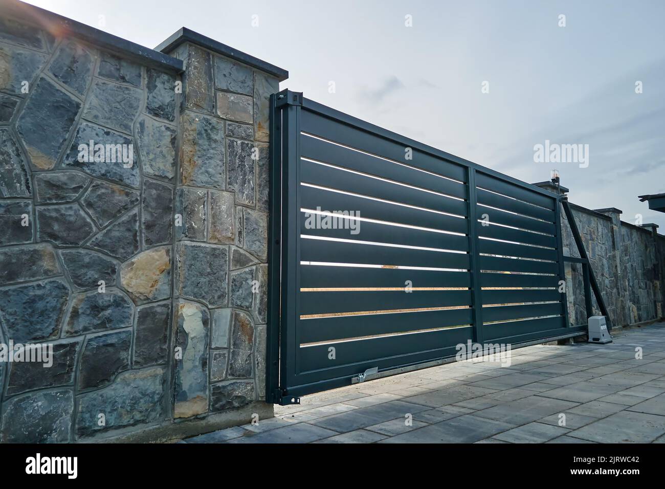 Wide automatic sliding gate with remote control installed in high stone