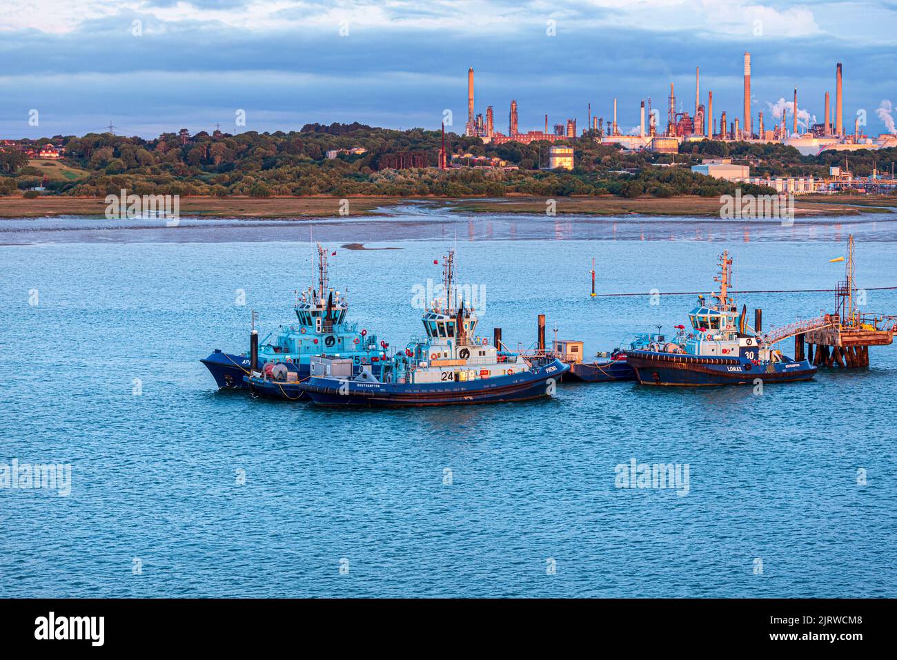 Tug boats Apex, Phenix & Lomax at dawn moored at the Esso owned Fawley Oil Refinery at Fawley, Hampshire UK Stock Photo