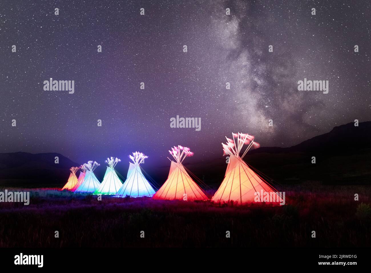 Madison Junction, United States of America. 17 August, 2022. Native American teepee lodges at the All Nations Teepee Village light at night under the Milky Way to mark the 150th anniversary of Yellowstone National Park August 17, 2022 in Madison Junction, Montana. The project by Mountain Time Arts features 13 teepee lodges that signify a new era of Indigenous inclusion and representation in Yellowstone National Park. Credit: Jacob W. Frank/NPS/Alamy Live News Stock Photo