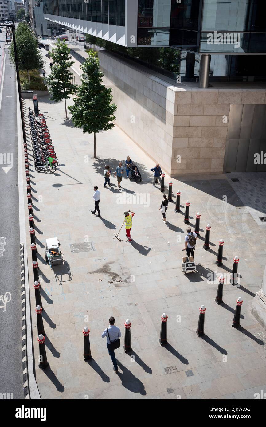 An aerial view of a street contractor removing litter along the pavement and around bollards in the City of London, aka The Square Mile, the capital's financial district, on 26th August 2022, in London, England. Stock Photo