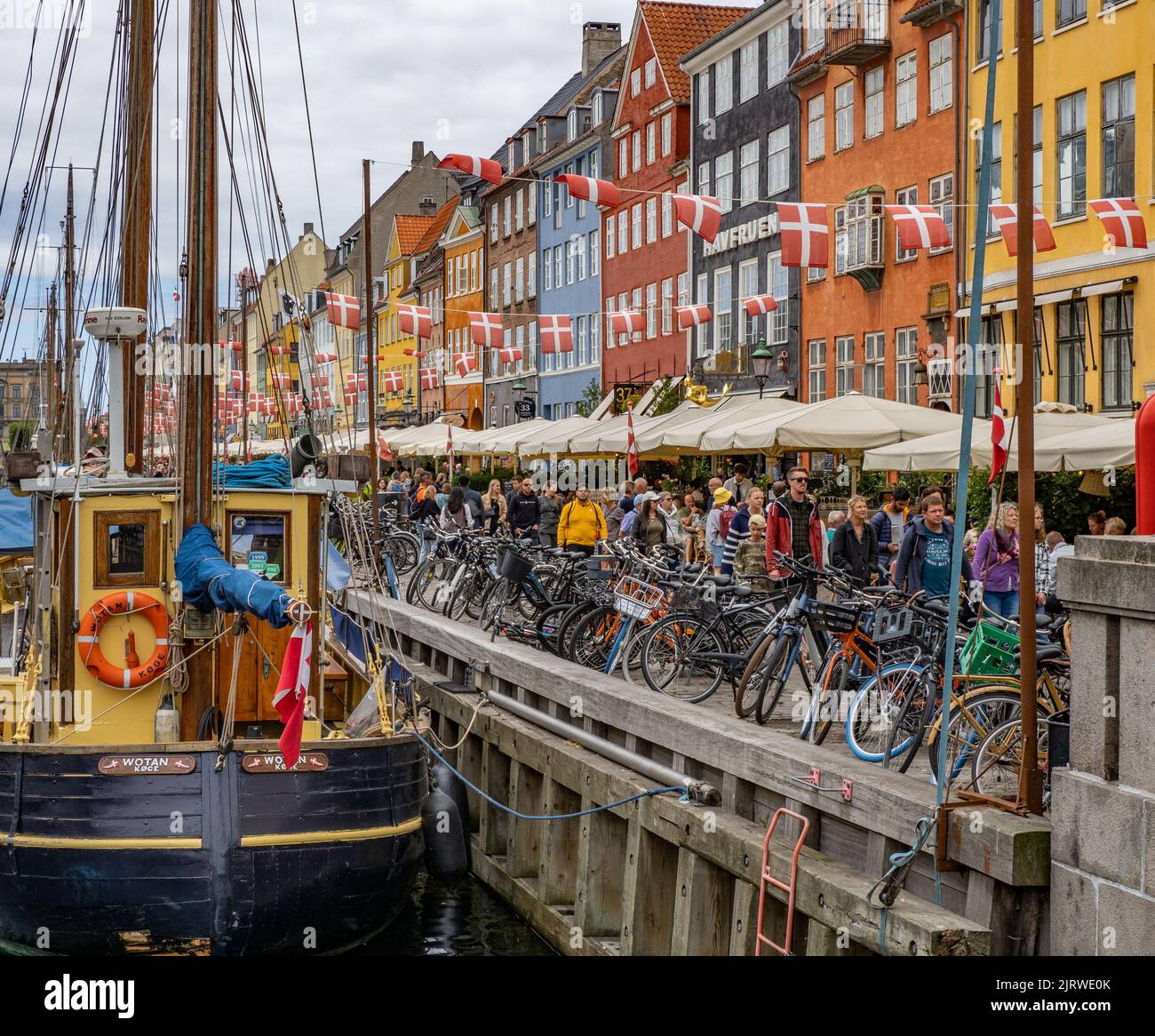 The popular tourist destination of Nyhavn an inlet of the sea lined with colourful 17th C houses cafes and bars and sailing boats - Copenhagen Denmark Stock Photo
