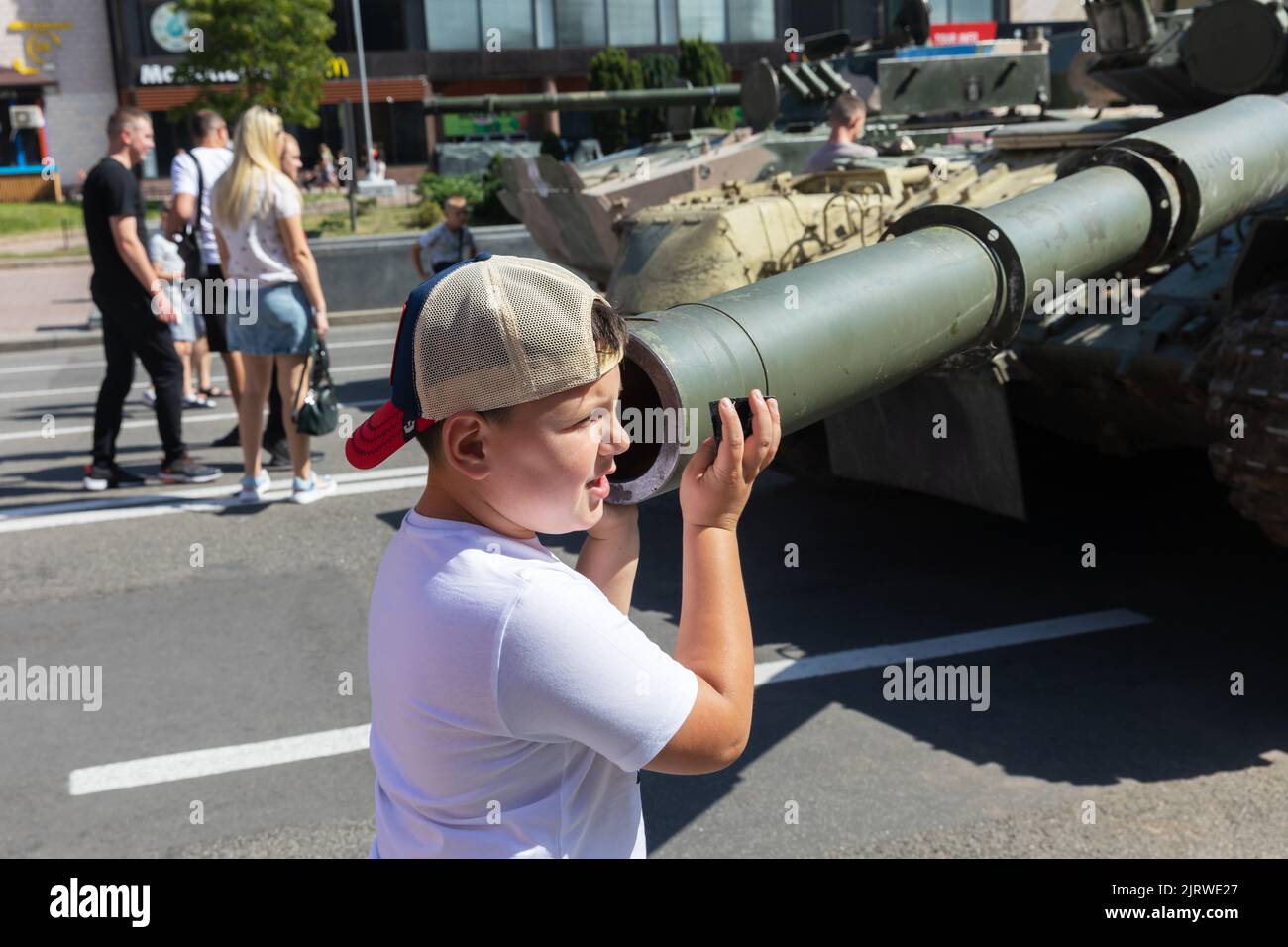 A teenager touches the barrel of a destroyed Russian tank. An exhibition of destroyed Russian equipment is being organized at Khreshchatyk. Six months ago, Russian military troops were deployed by Russian president Vladimir Putin to invade Ukraine. He reportedly reckoned that they would capture Kyiv in three days, Stock Photo