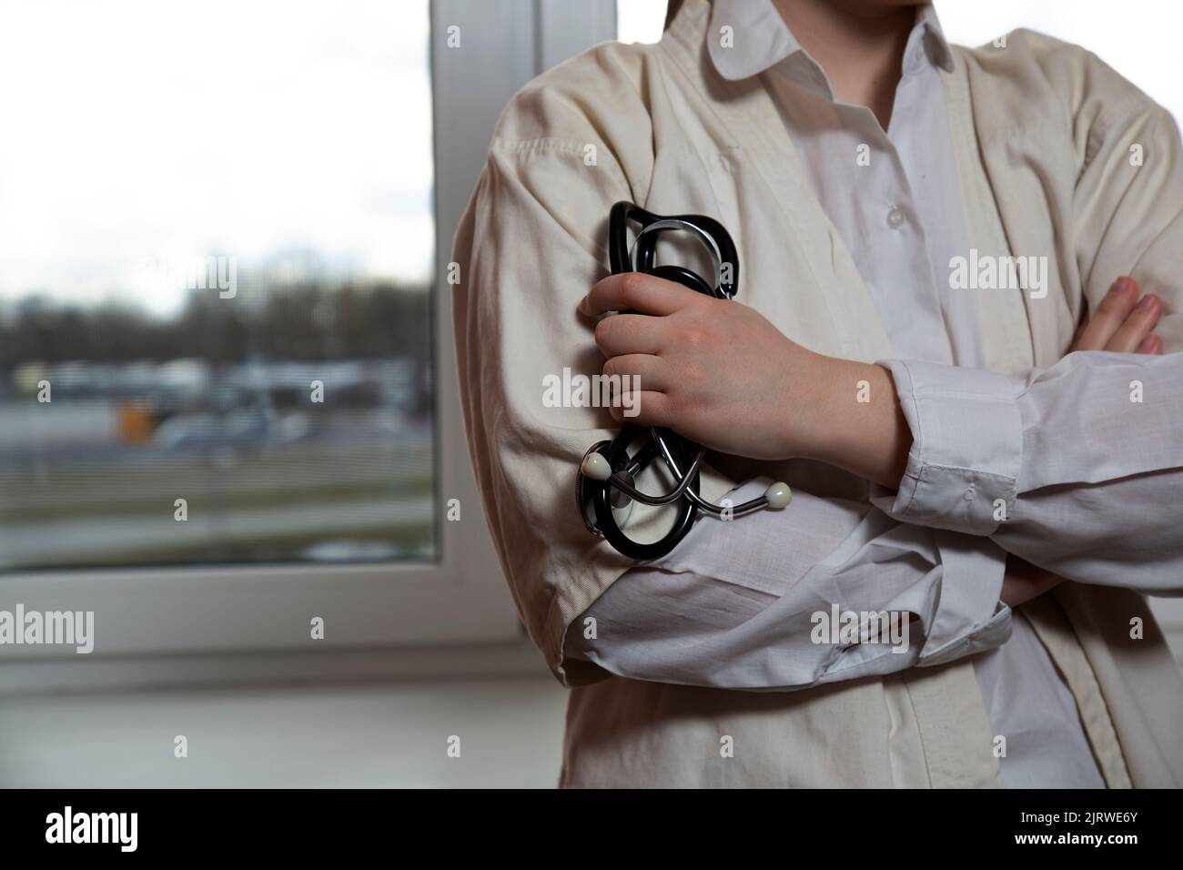 The doctor holds a stethoscope in the background of the window. Stock Photo