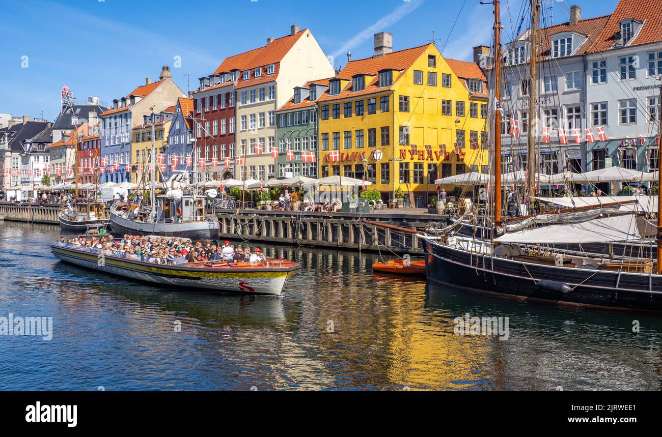 The popular tourist destination of Nyhavn an inlet of the sea lined with colourful 17th C houses cafes and bars and sailing boats - Copenhagen Denmark Stock Photo