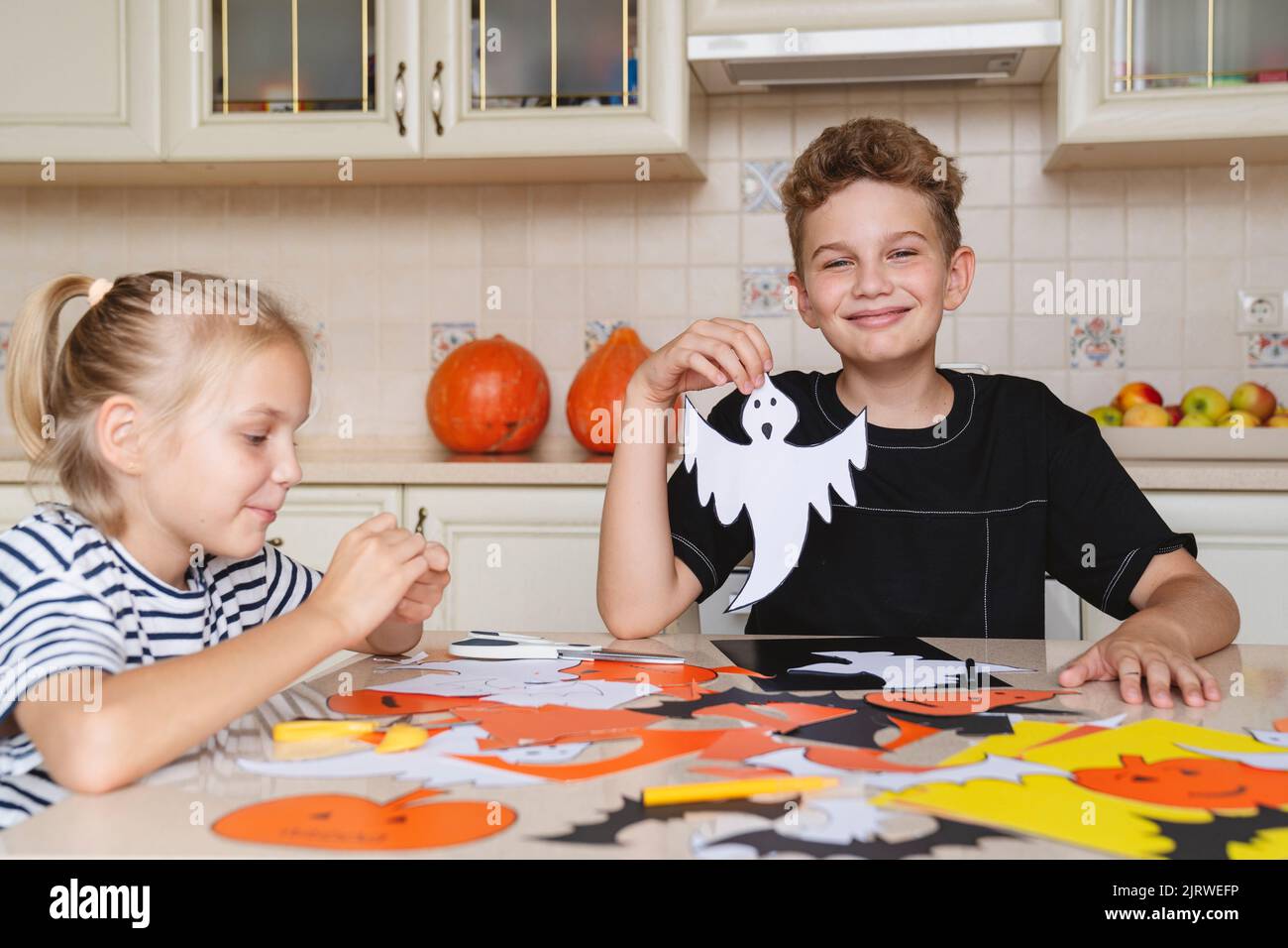 Children prepare crafts made of colored paper for the Halloween. Stock Photo