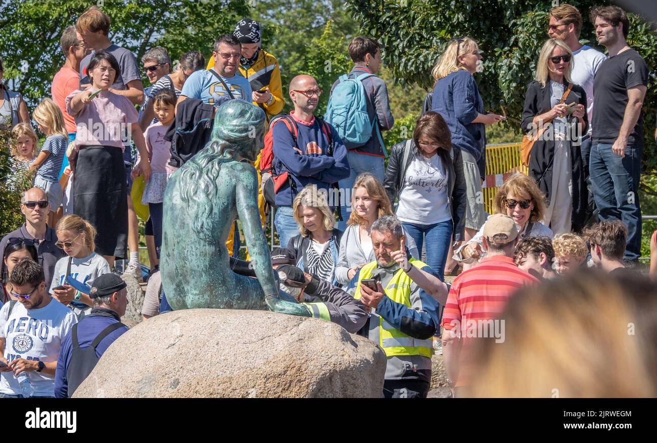 Tourists in Copenhagen Denmark visiting but largely ignoring the bronze sculpture of the Little Mermaid by Edvard Eriksen by the city's harbour Stock Photo