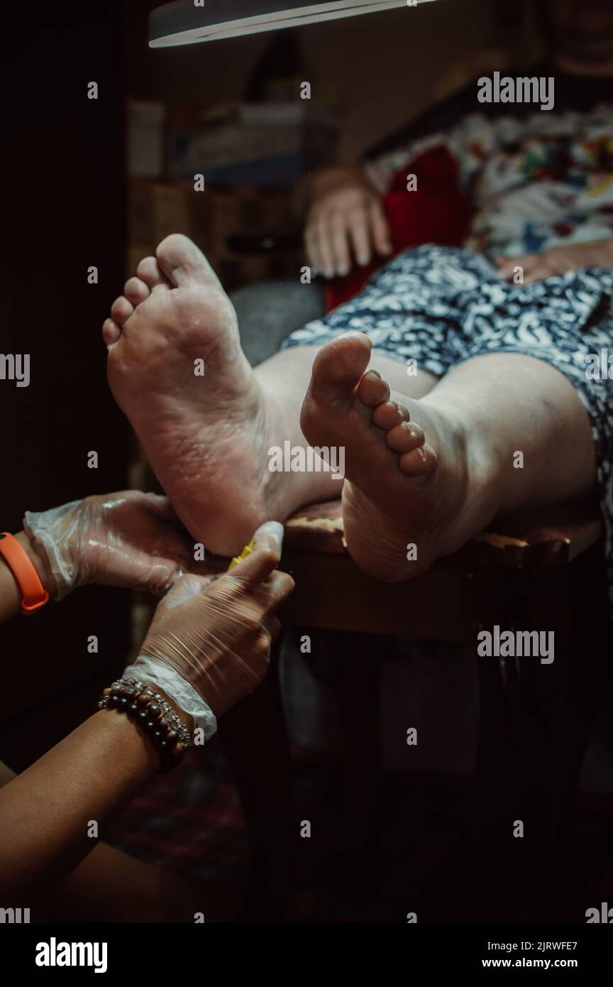 Pedicurist takes care of skin of client's feet Stock Photo