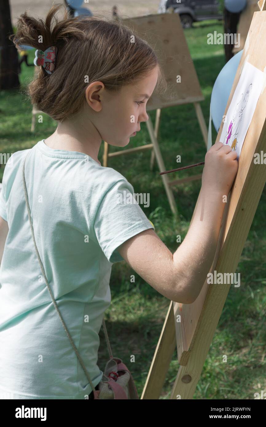 Girl is painting on an easel outdoors on a summer day Stock Photo Alamy