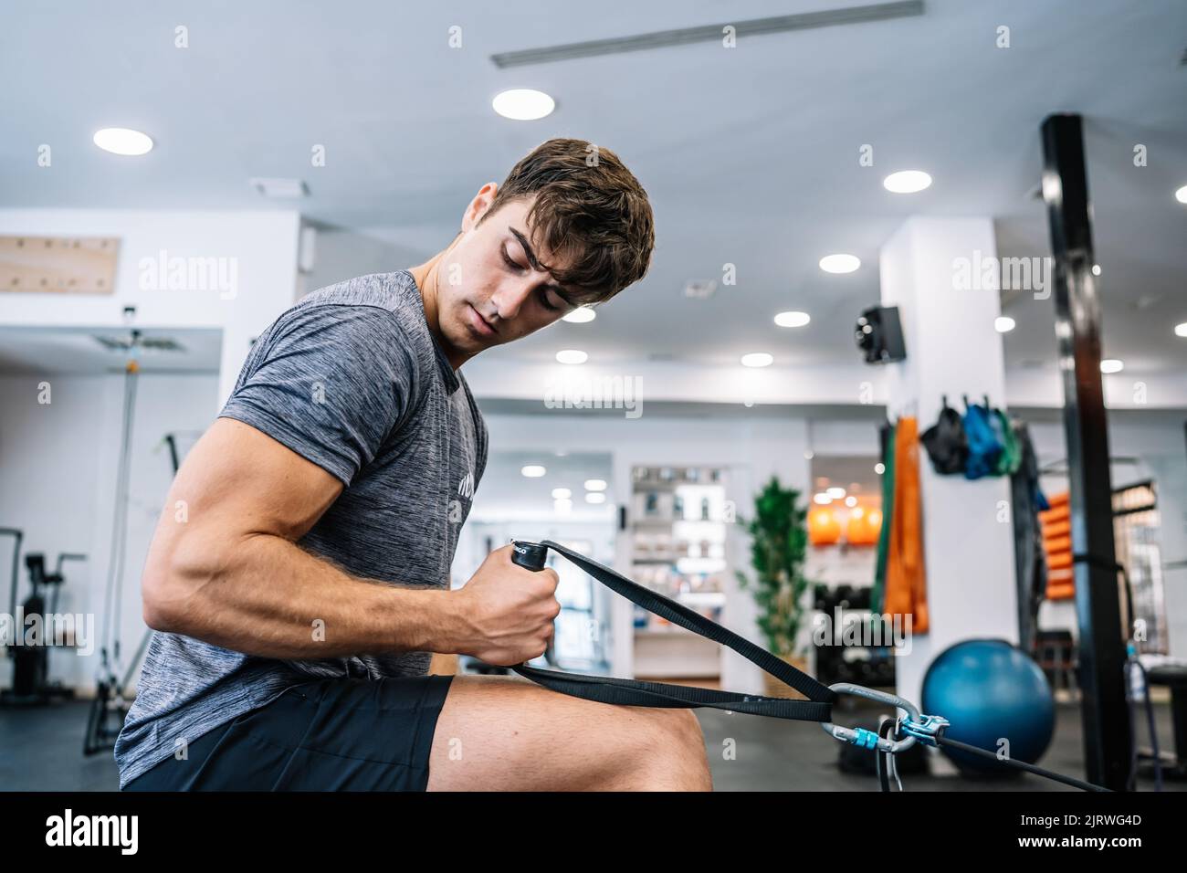 Side view of muscular male athlete pulling rope of rowing machine and