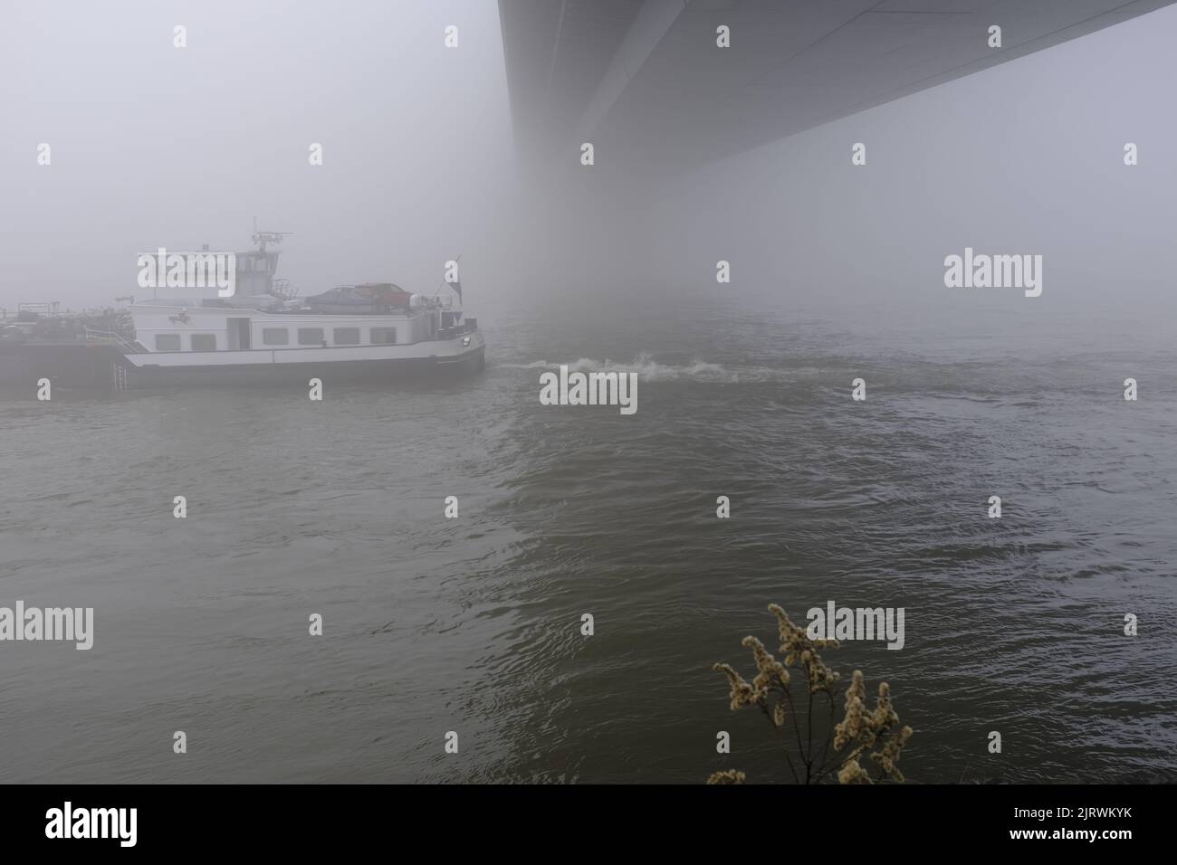 16.12.2021, Duesseldorf, Nordrhein-Westfalen, Deutschland - Frachtschiff auf dem Rhein in Duesseldorf bei Nebel unter der Oberkasseler Bruecke Stock Photo