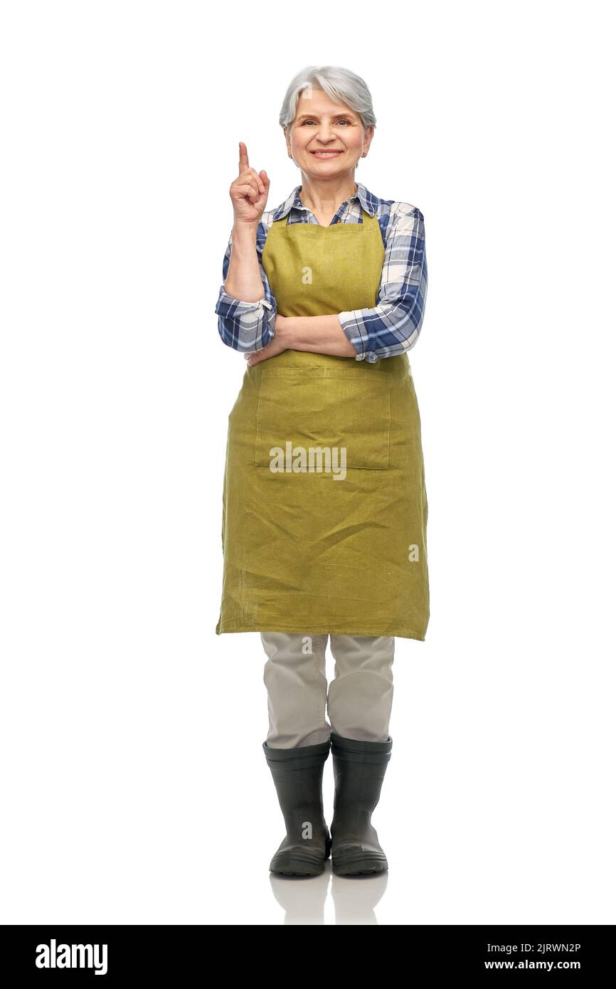 happy old woman in garden apron pointing finger up Stock Photo