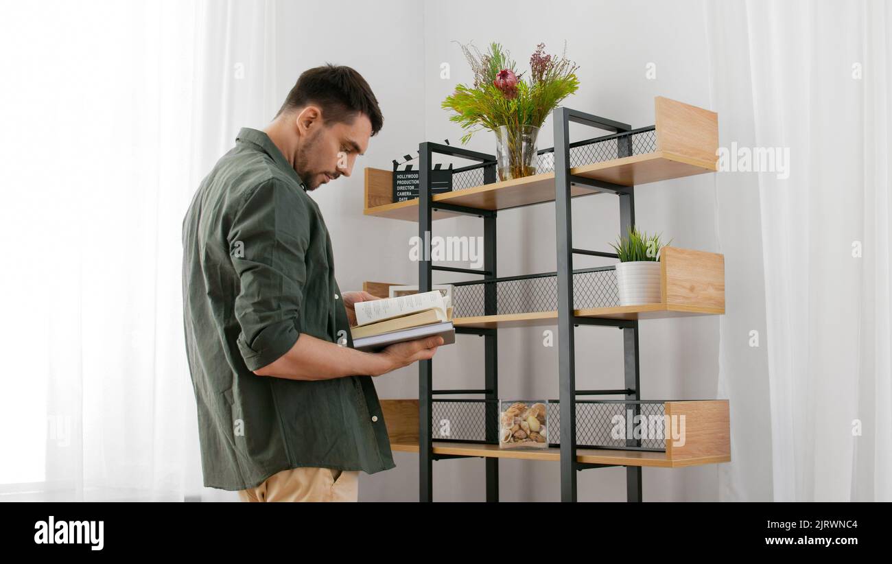 man with books decorating home and arranging shelf Stock Photo - Alamy