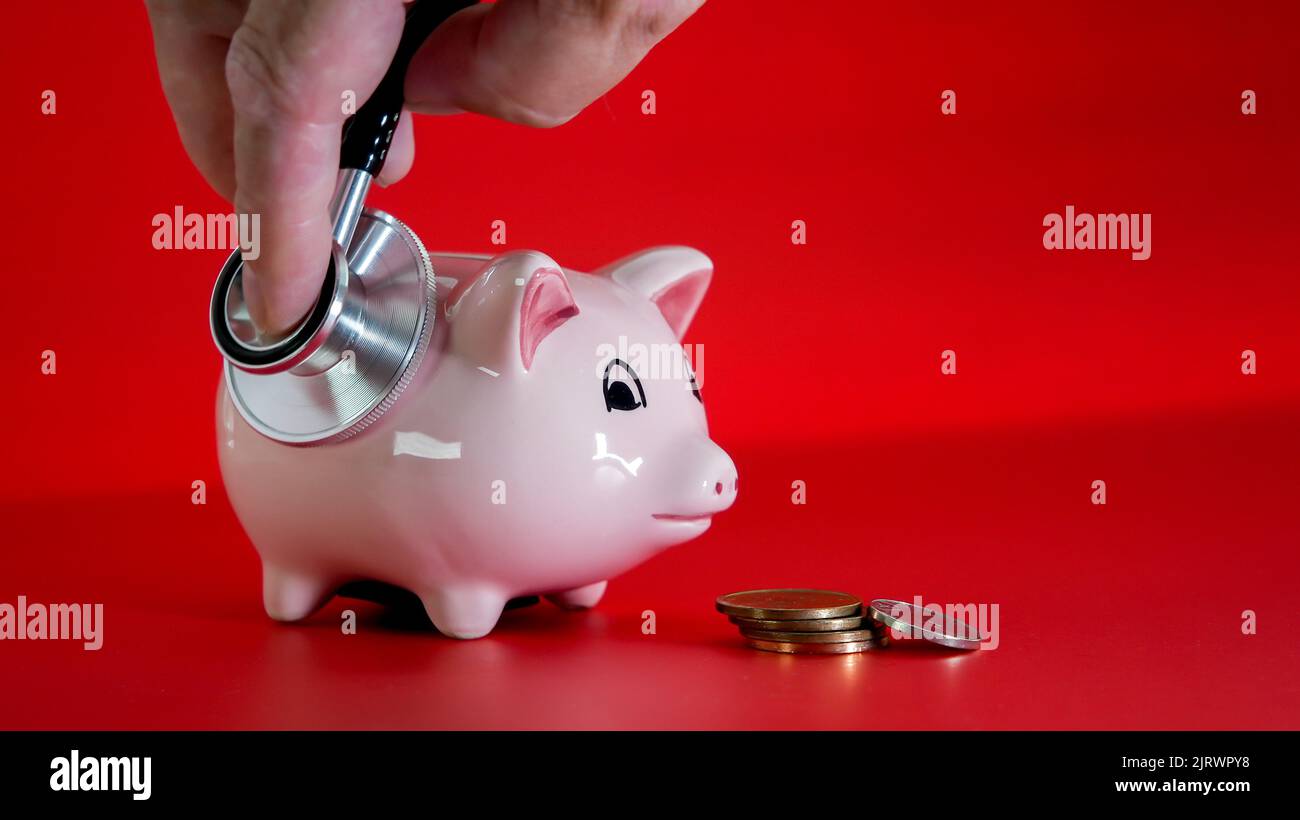 Checking pig saving bank with stethoscope on red background Stock Photo