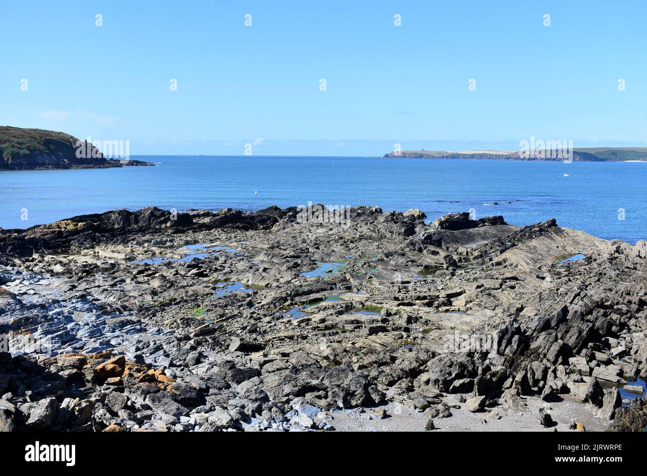 Rocky foreshore and view out of the Milford Haven waterway, West Angle, Pembrokeshire, Wales Stock Photo