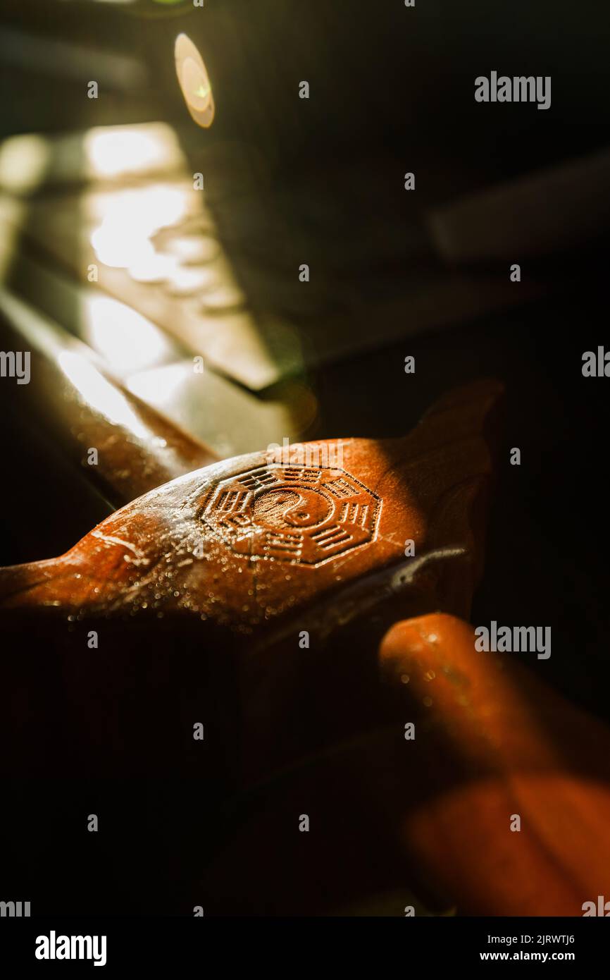 A closeup picture of sunshine shining on a wooden sword with the yin and yang symbol on the handle Stock Photo