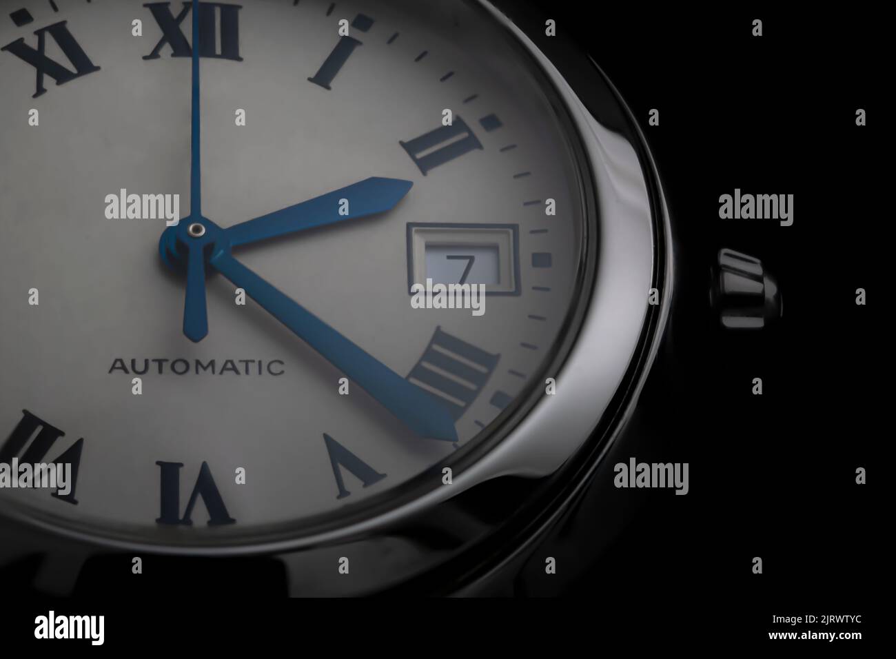 Close-up of an automatic Swiss watch with blue hands, date window and steel round case Stock Photo