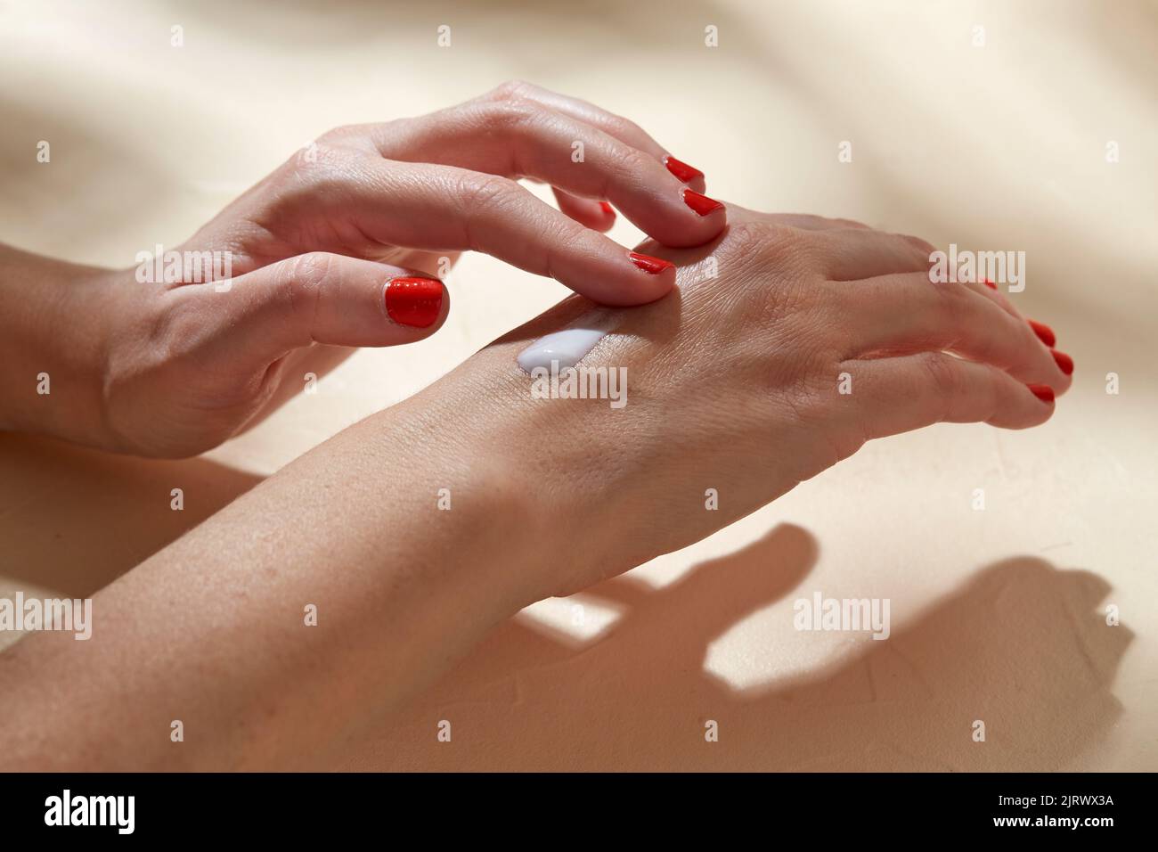 female hands applying moisturizer to skin Stock Photo